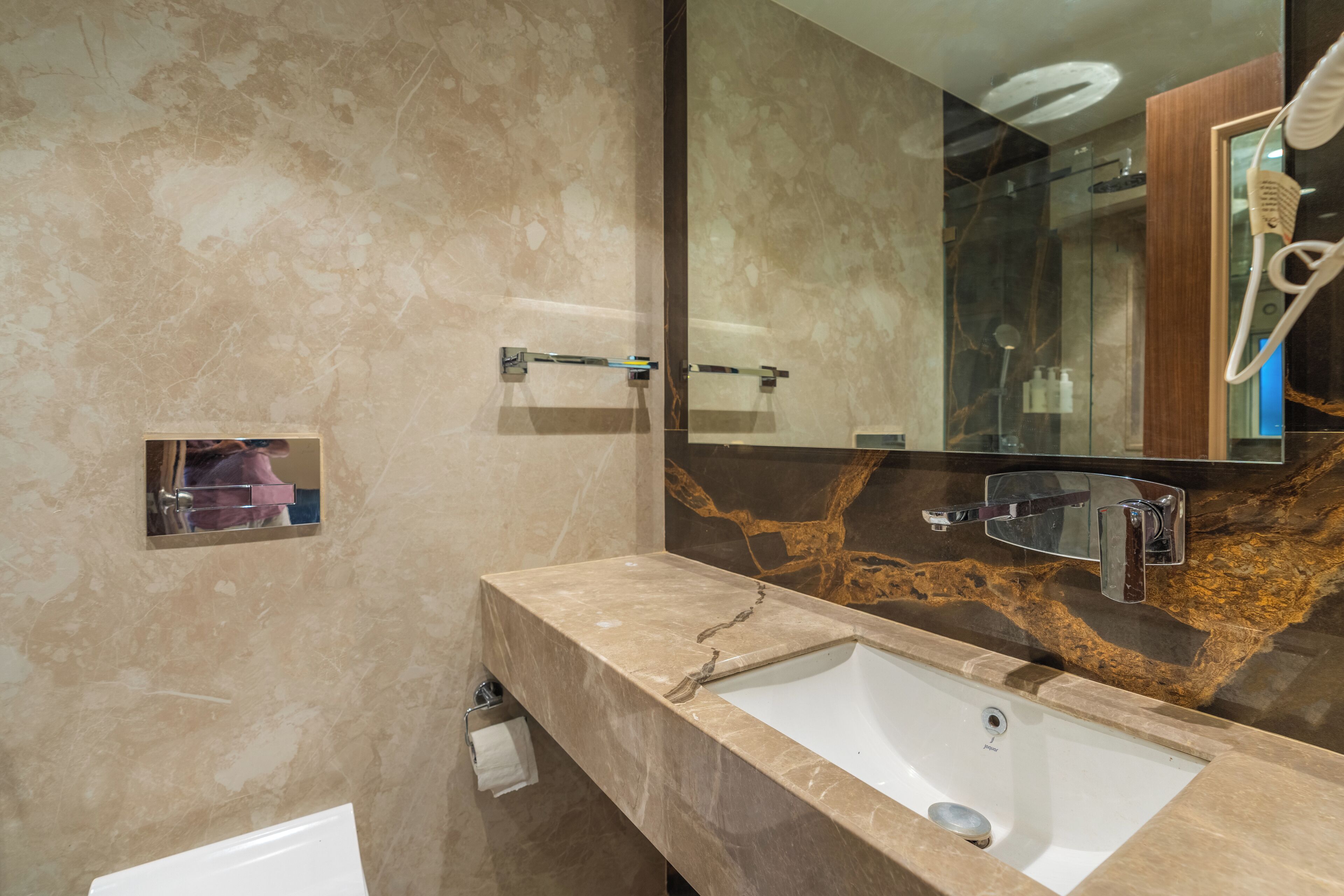 Une salle de bain avec un lavabo en marbre, un grand miroir et un porte-serviettes.