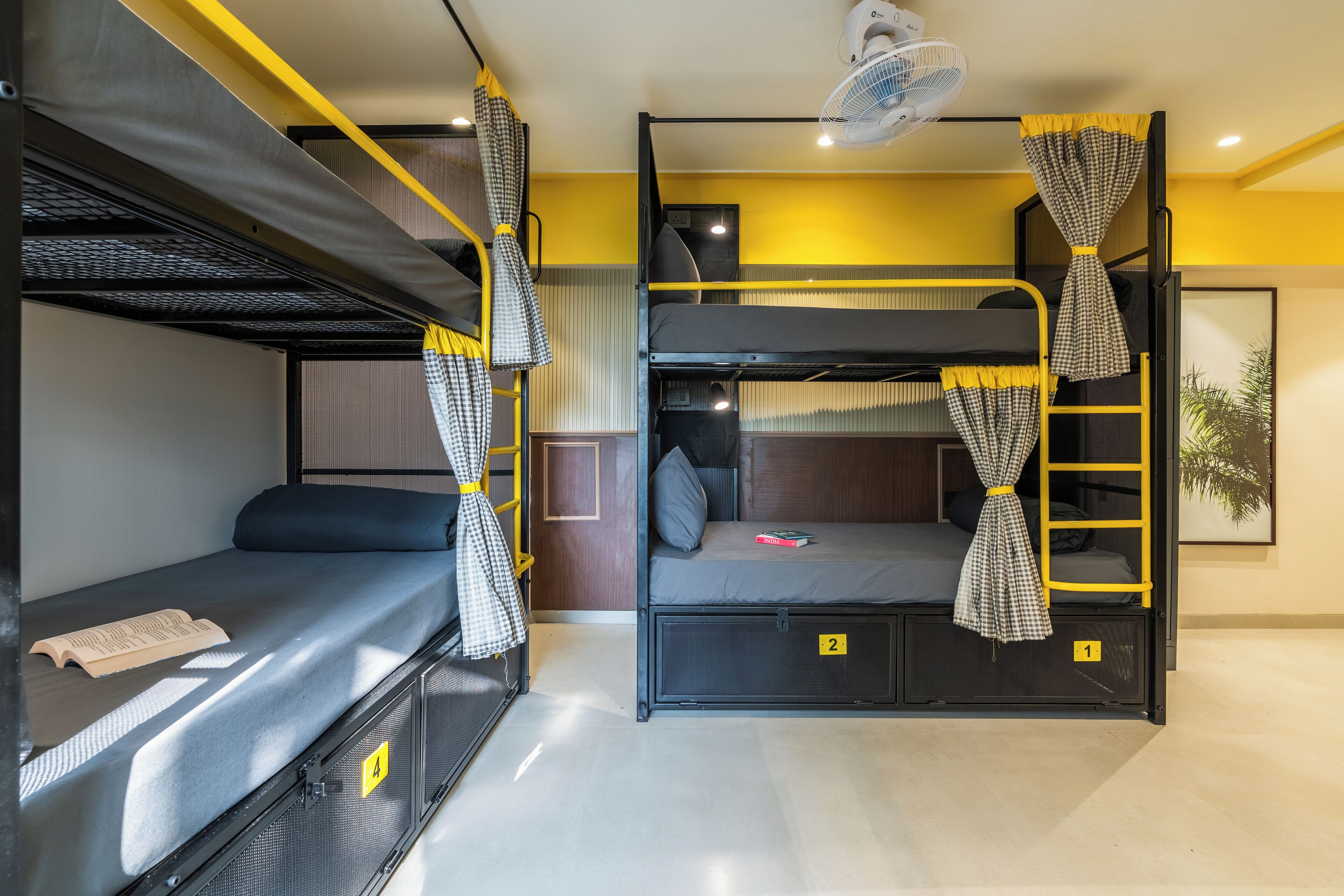 Una camera con un letto a castello, una scala, una ventola e una pianta.