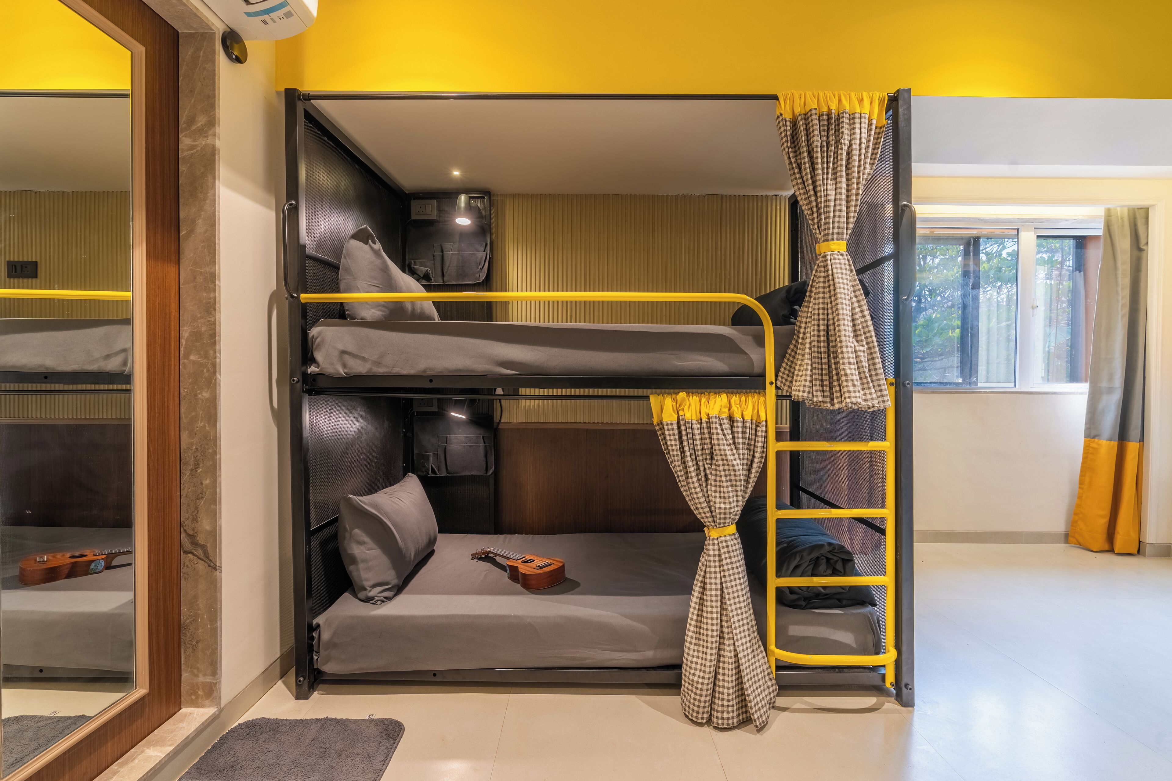 A bunk bed room with a mirror, a guitar, and a window with curtains.