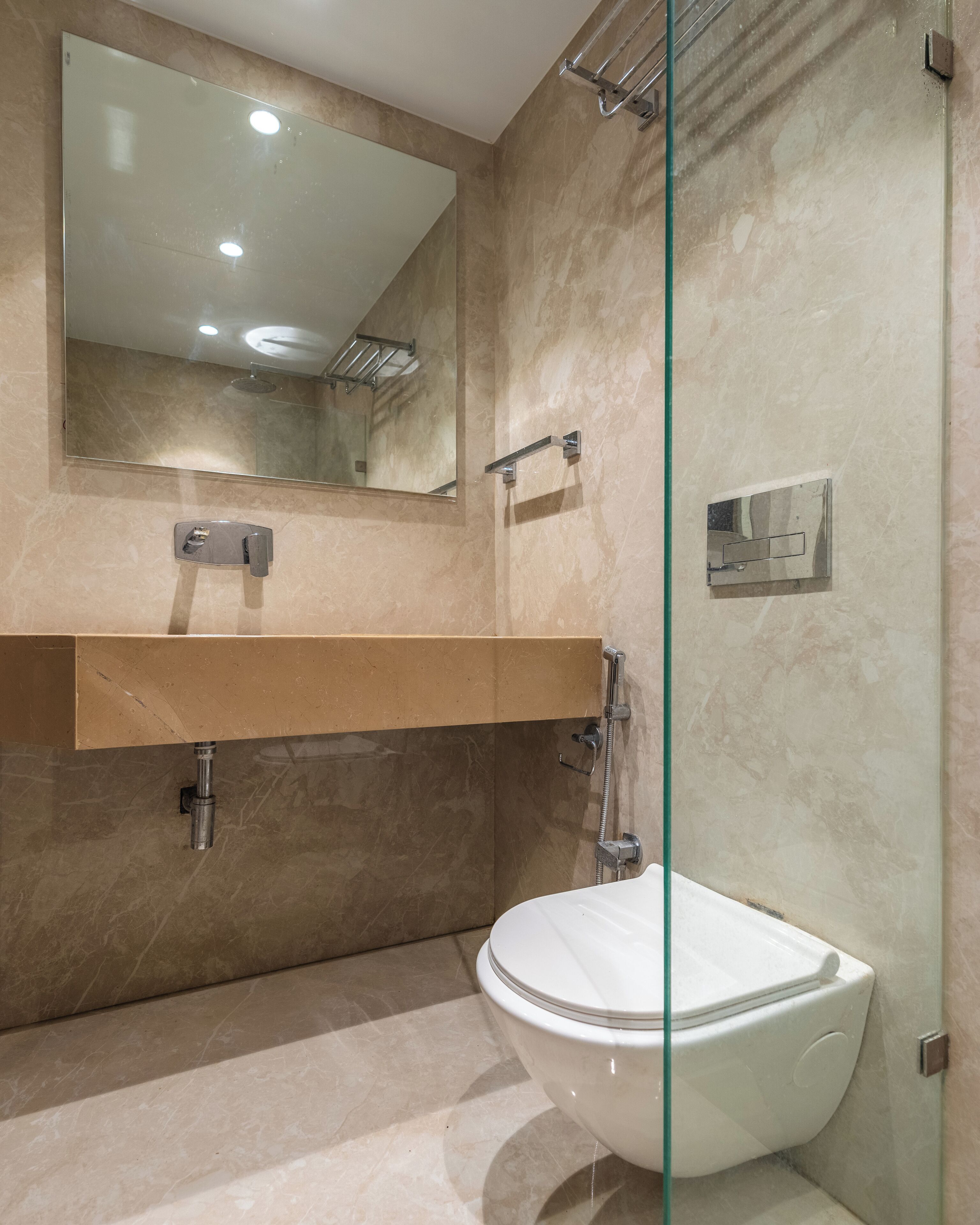 Une salle de bain moderne avec une douche à parois de verre, des toilettes blanches, un meuble-lavabo avec un miroir et un porte-serviettes.