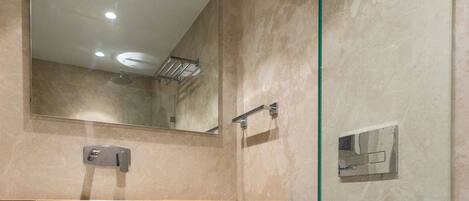 Une salle de bain moderne avec une douche à parois de verre, des toilettes blanches, un meuble-lavabo avec un miroir et un porte-serviettes.