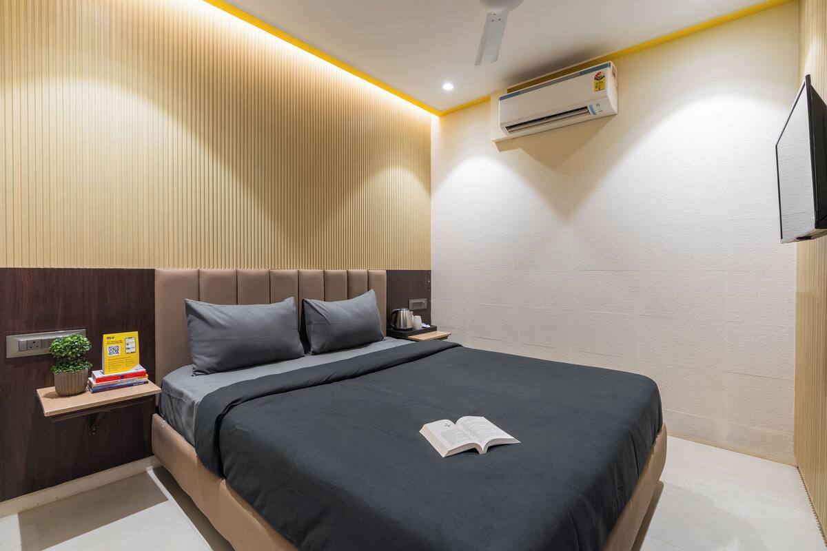 A modern bedroom with a bed, bedside tables, a nightstand, a wall-mounted air conditioner, and a TV.