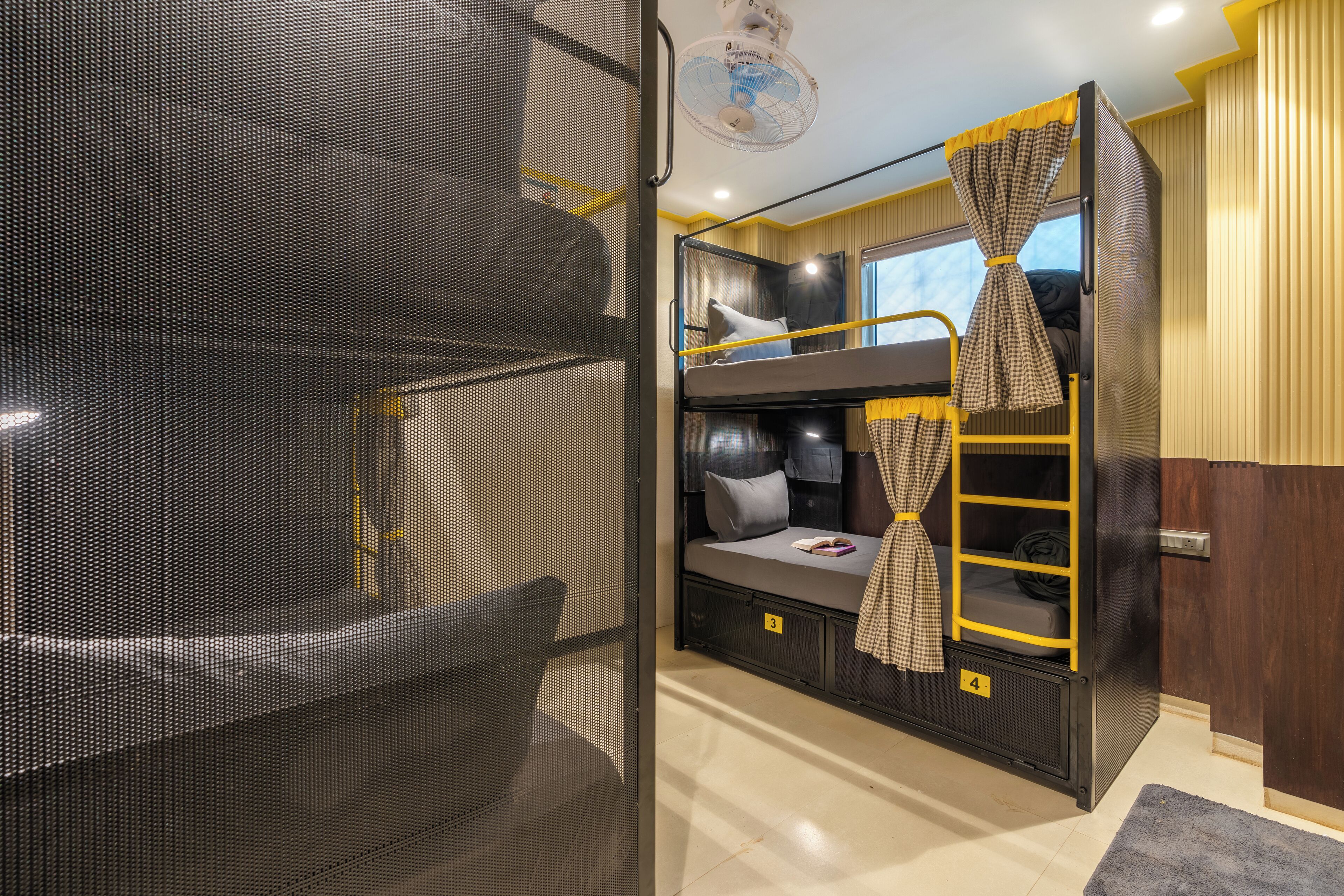 Une chambre avec un lit superposé, un moustiquaire, une échelle et une fenêtre avec des rideaux.