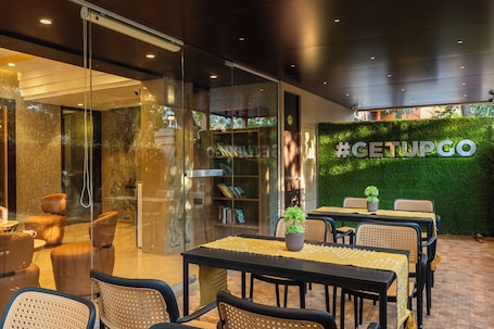A modern indoor dining area with glass walls, a #GETUPGO sign, and a green wall.