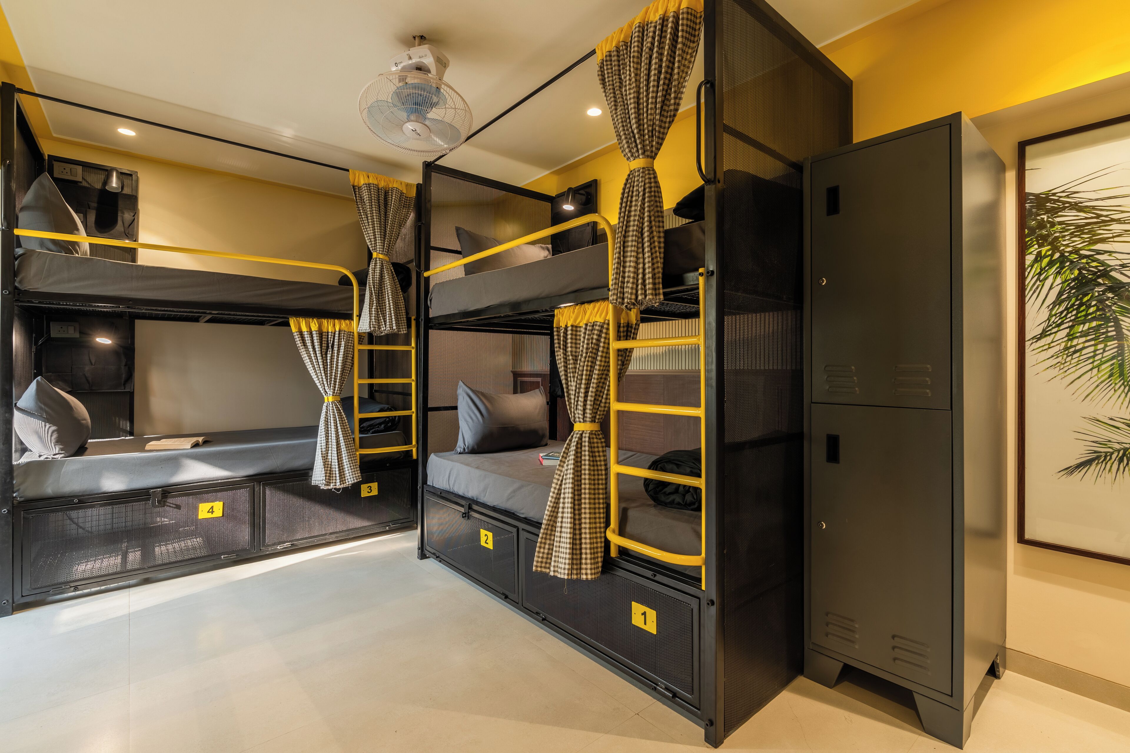 A bunk bed room with a ceiling fan, a wardrobe, and a framed plant on the wall.