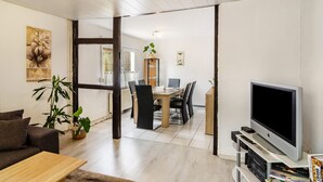 Een moderne woonkamer met een bank, een salontafel, een televisie en een eethoek met een tafel en stoelen.