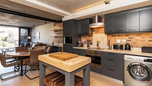 Una cucina moderna con mobili scuri, un tavolo in legno e una lavatrice integrata.