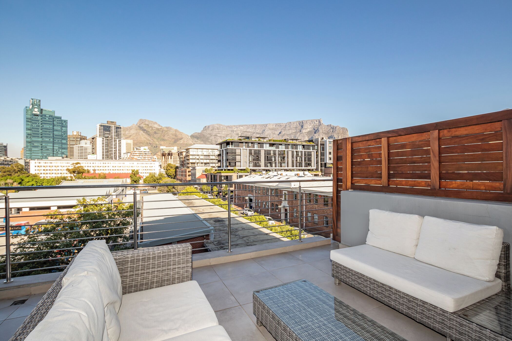 A rooftop terrace with outdoor seating, a view of the cityscape, and mountains in the background.