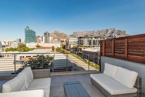 A rooftop terrace with a view of a cityscape and mountains. - The Docklands Two Bed Superior Apartment (Cape Town)