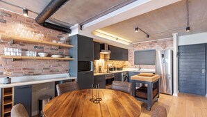 Una cucina moderna con parete in mattoni, scaffali in legno e un tavolo rotondo in legno.