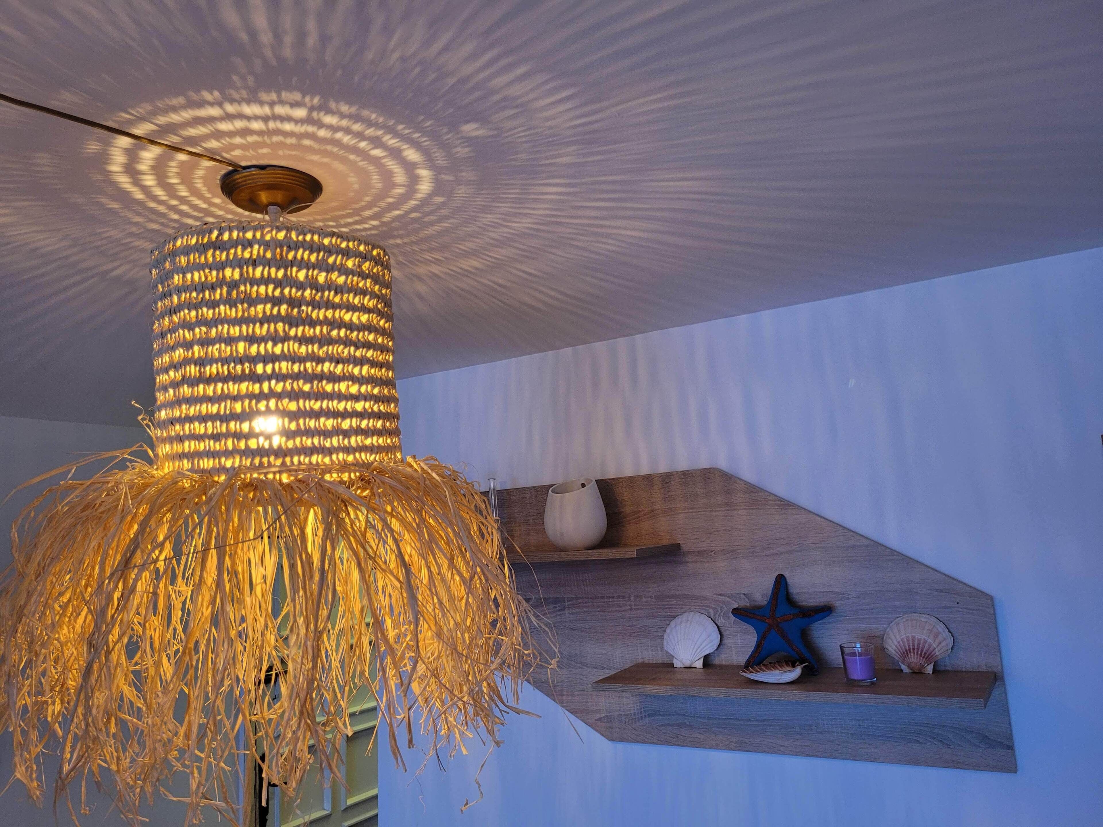 A hanging light fixture with a woven design and a starfish decoration on a shelf.