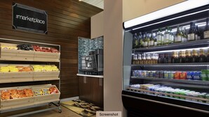 Una tienda de comestibles con un letrero que dice 'marketplace', estantes con bocadillos, un horno para pizza y una vitrina refrigerada de bebidas.