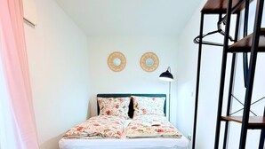 A bedroom with a bed, a rug, a shelf, and a light fixture. - Charming apartment | balcony, close to the center, self check-in (Augsburg)