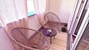 A balcony with two wicker chairs, a small table with a candle, and a potted plant. - Charming apartment | balcony, close to the center, self check-in (Augsburg)