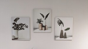 A wooden desk with a plant, a small vase, and a candle. There are three framed pictures on the wall above the desk. - Aux Fleurs des Champs (Lautenbach)