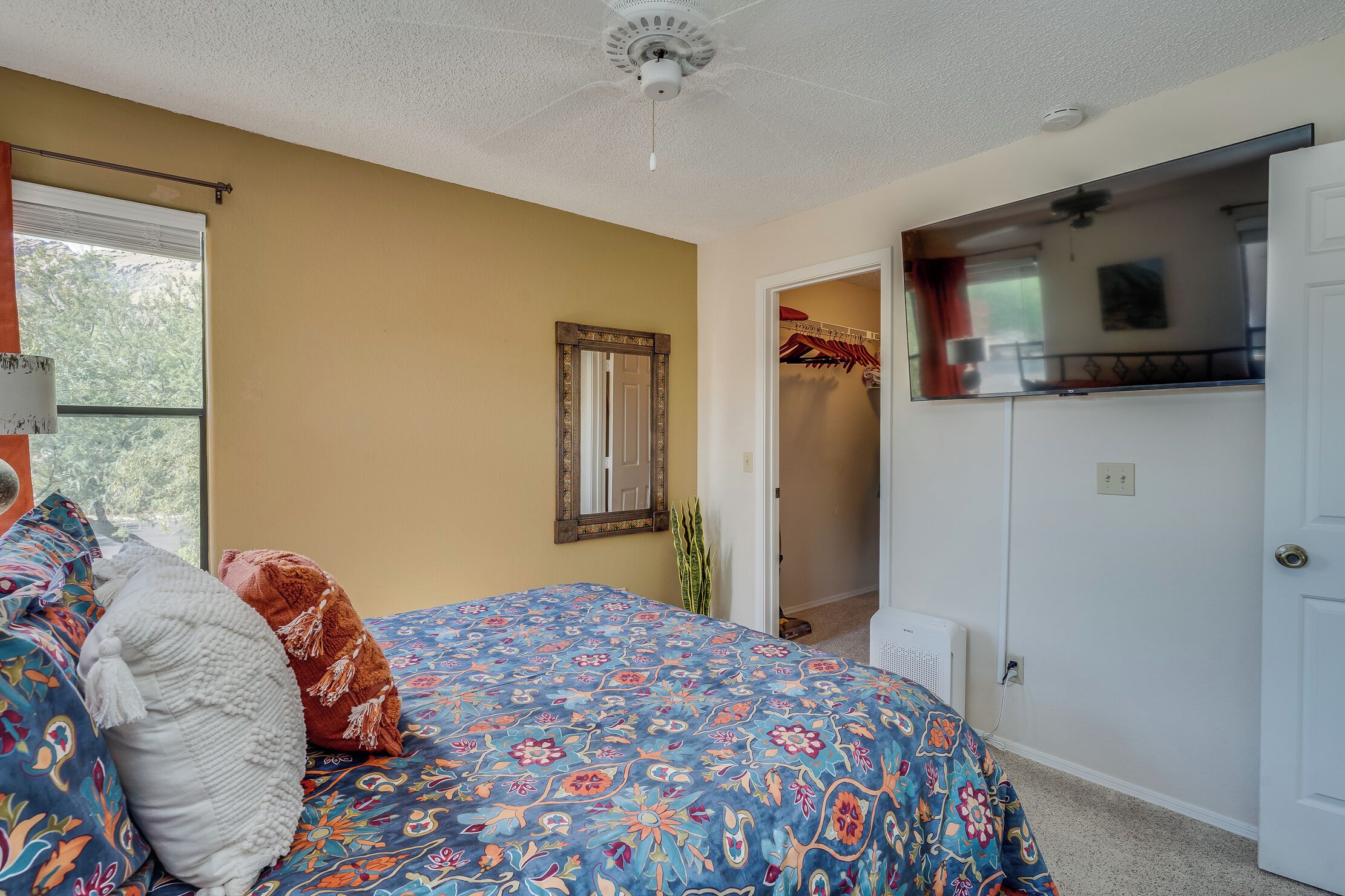 Ein Schlafzimmer mit Bett, Spiegel, Kleiderschrank und einer Tür zum Badezimmer.