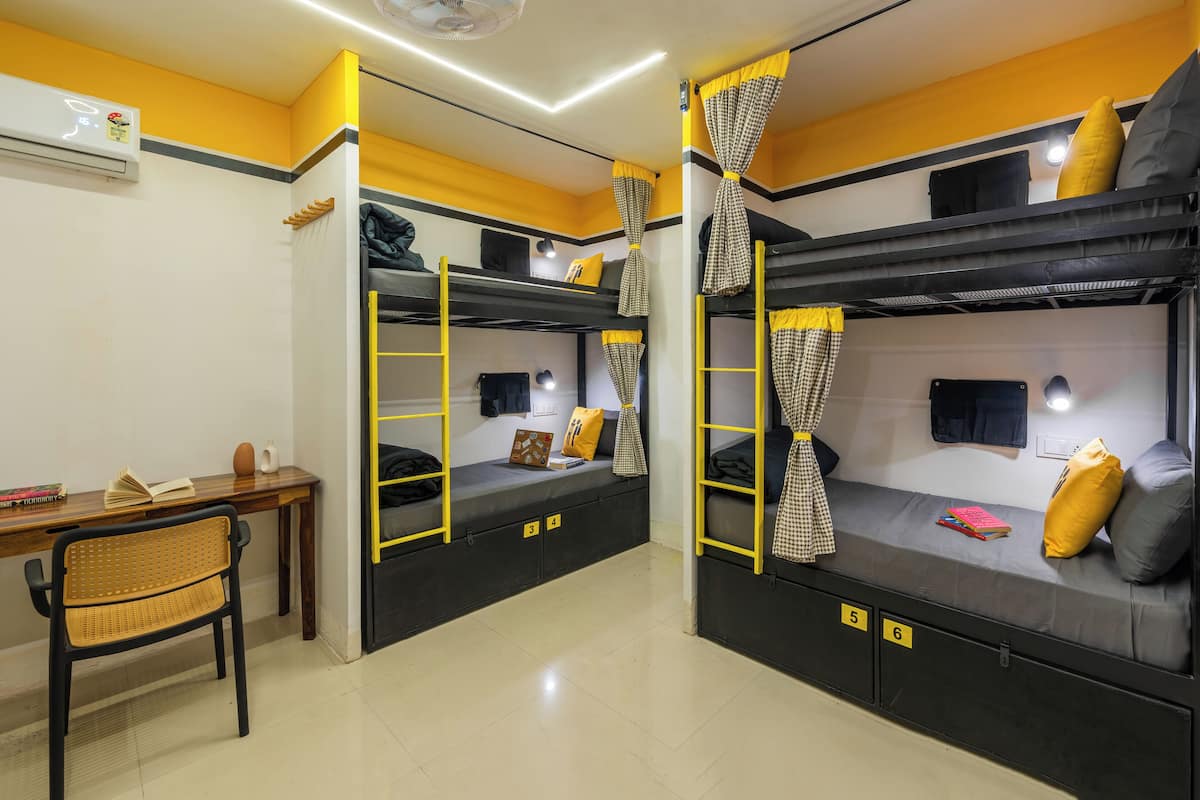 A dormitory room with bunk beds, a desk, and a chair.