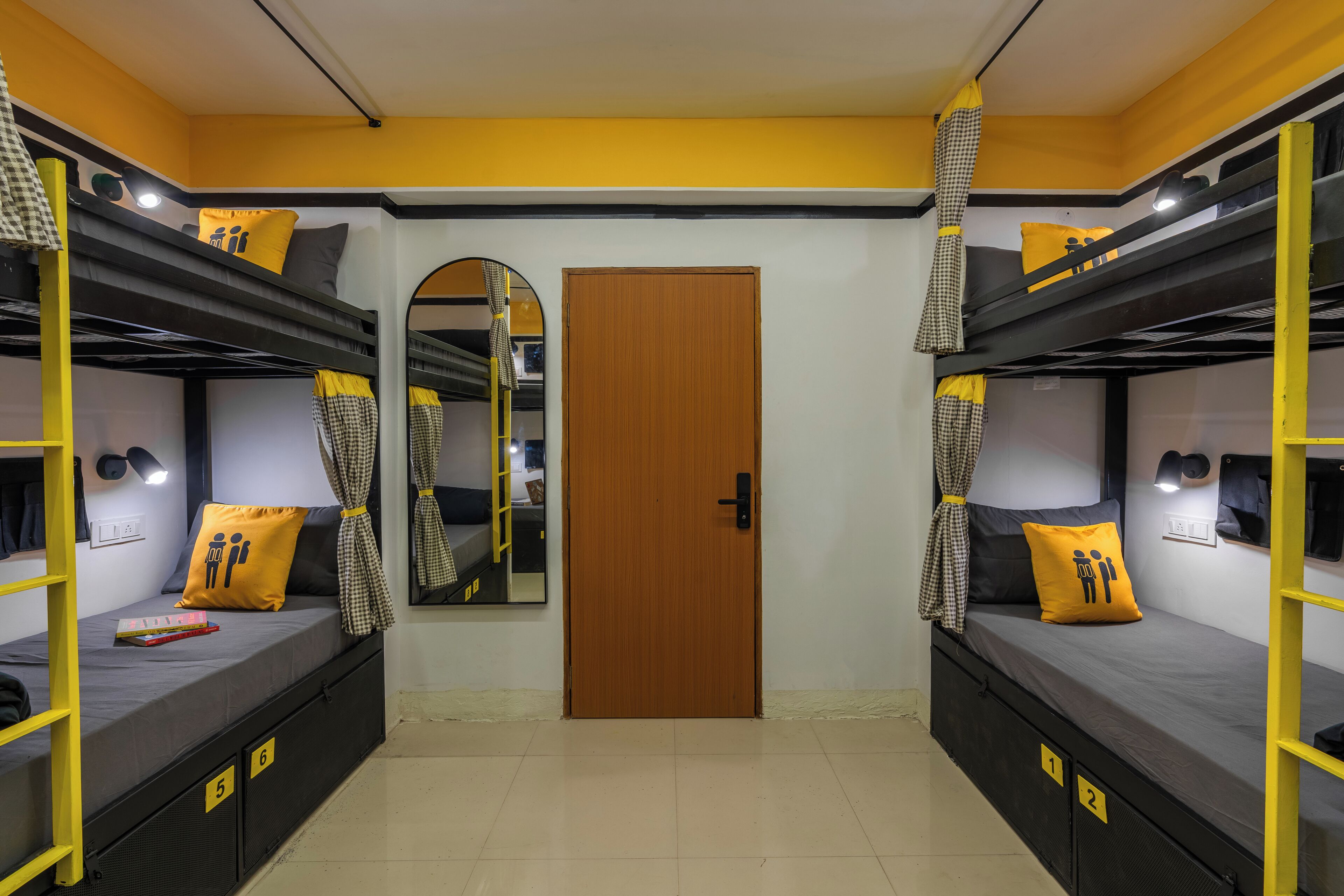 A dormitory room with bunk beds, a wooden door, and a mirror.