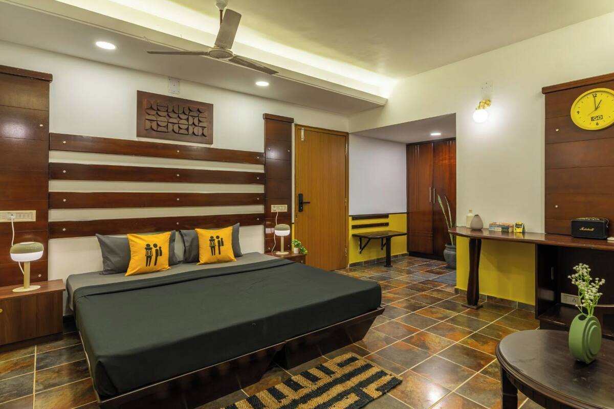 A modern bedroom with a bed, bedside tables, a desk, and a clock.