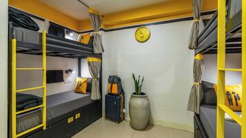 A bunk bed room with a suitcase, a clock, and a potted plant.