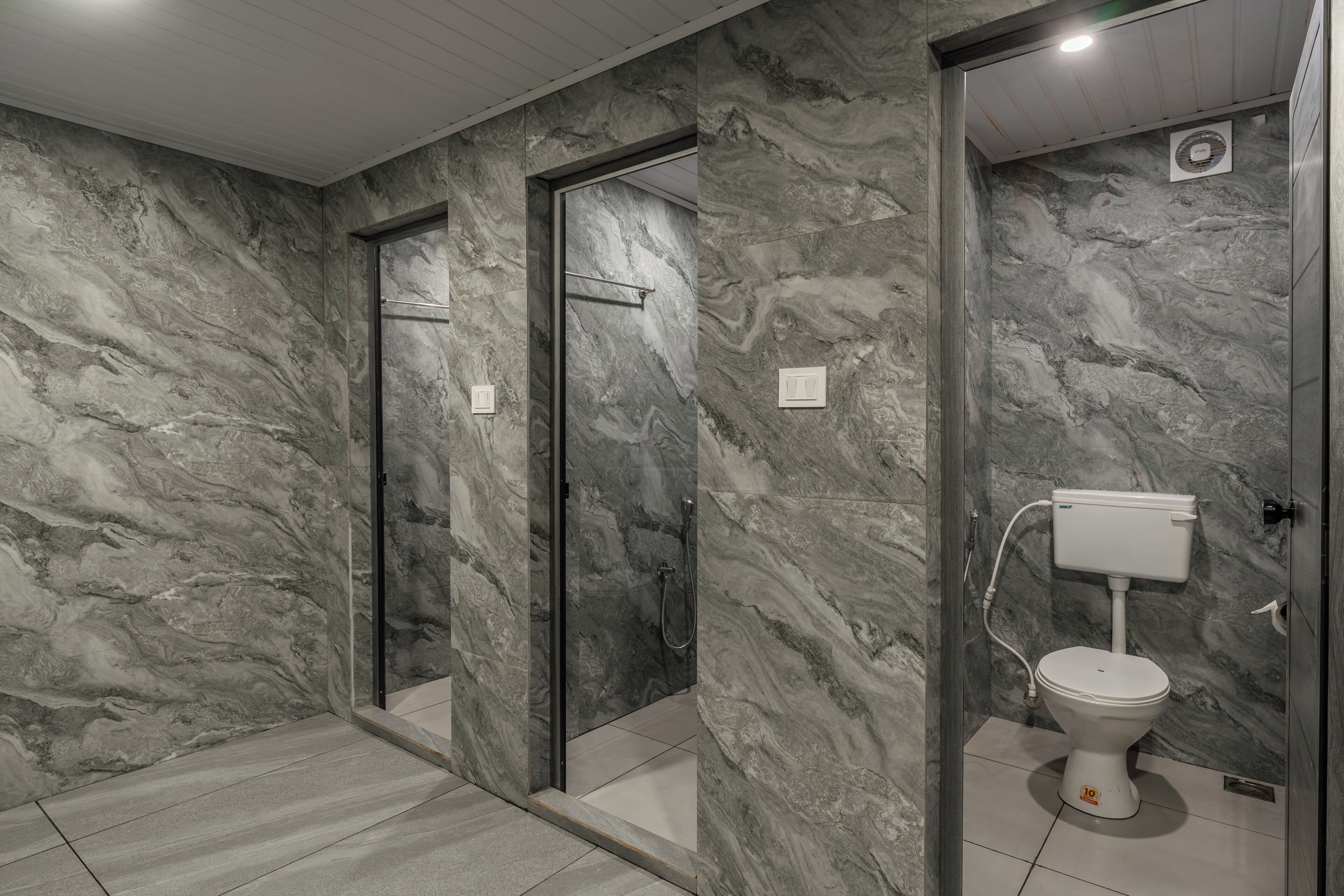 A bathroom with marble walls, a shower, and a toilet.