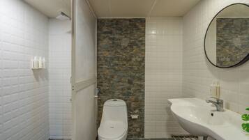 A bathroom with a toilet, a sink, and a shower area.