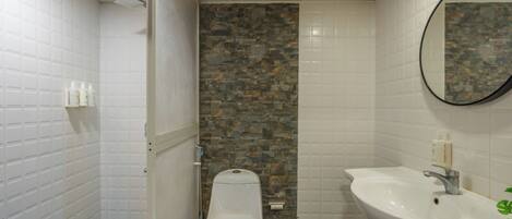 A bathroom with a toilet, a sink, and a shower area.