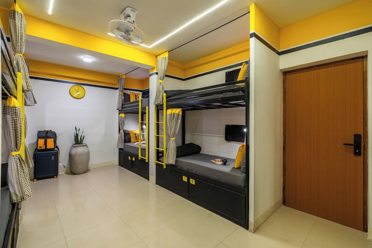 A bunk room with bunk beds, a clock, a potted plant, and a suitcase.
