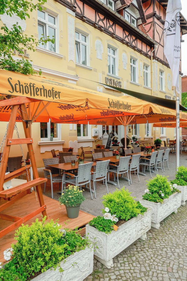Ein Außenbereich mit Tischen, Stühlen, einer Holzleiter und Blumentöpfen.