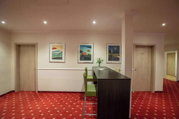 A hotel lobby with a reception desk, green chairs, framed artwork on the walls, and carpeted floors. - Hotel Union Salzwedel (Salzwedel)