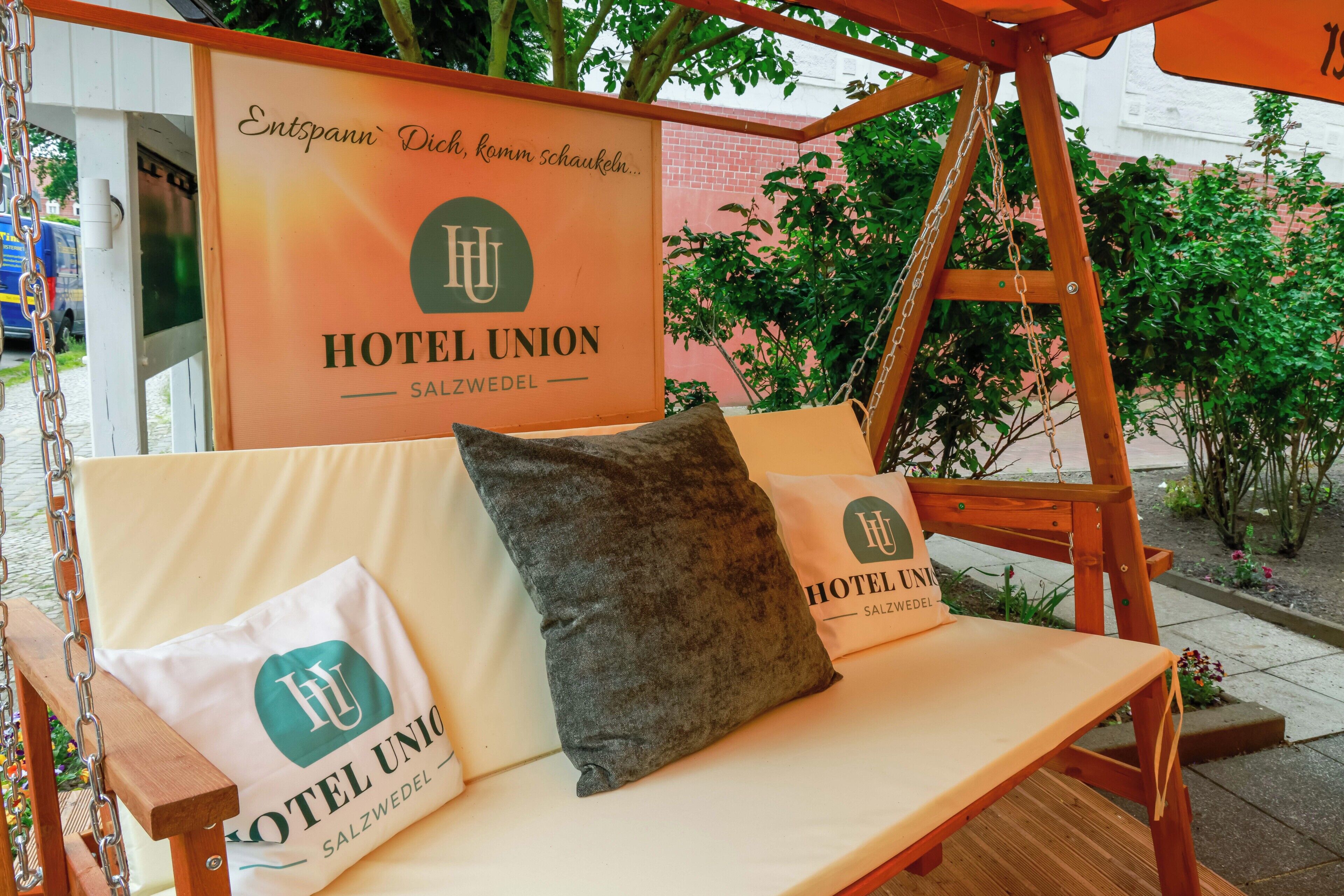 A wooden swing chair with pillows and a sign for Hotel Union Salzburg.
