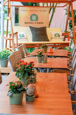 Une table en bois, ornĂ©e de plantes en pot, et une enseigne indiquant lâhĂŽtel Union.