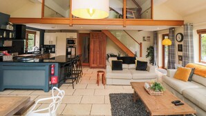 Amplia sala de estar con cocina, mesa de comedor y sofá. Una escalera conecta la sala de estar con un nivel superior.