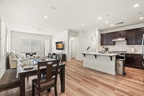 A spacious kitchen with dark cabinets, a marble countertop, and a stainless steel range hood. - Comfort Style Home Near the Airport (Ontario)
