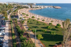 A coastal area with a beach, parking lot, and a road curving around the beach. - Beachside Retreat in Glyfada (Glyfada)