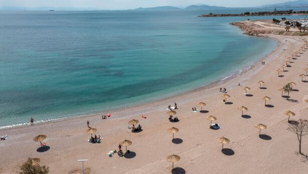 Una platja amb files de sombrerets i una vista clara del mar.