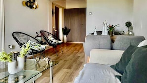 Un saló modern amb un sofà, dues cadires negres, una taula de centre de vidre i elements decoratius.