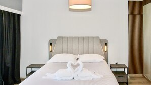 Habitació d'hotel amb un llit gran, dues taules de nit, un capçal de llit i una làmpada penjada a la paret.