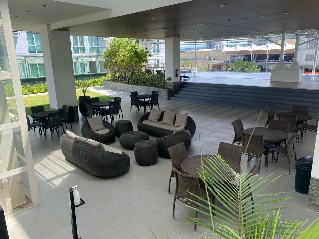 A spacious outdoor seating area with modern furniture, including sofas and chairs, and a view of a building in the background.