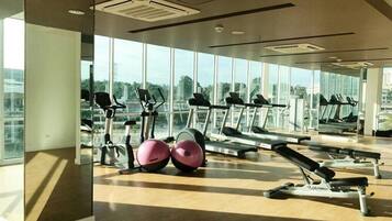 Un gimnasio con cintas de correr, pelotas de ejercicio y un ventanal con vistas a la ciudad.