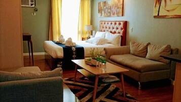 A compact living space with a bed, sofa, and a dining table.