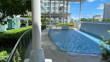 Ein Dachpool mit Glasgeländer, umgeben von Grünflächen und modernen Gebäuden.
