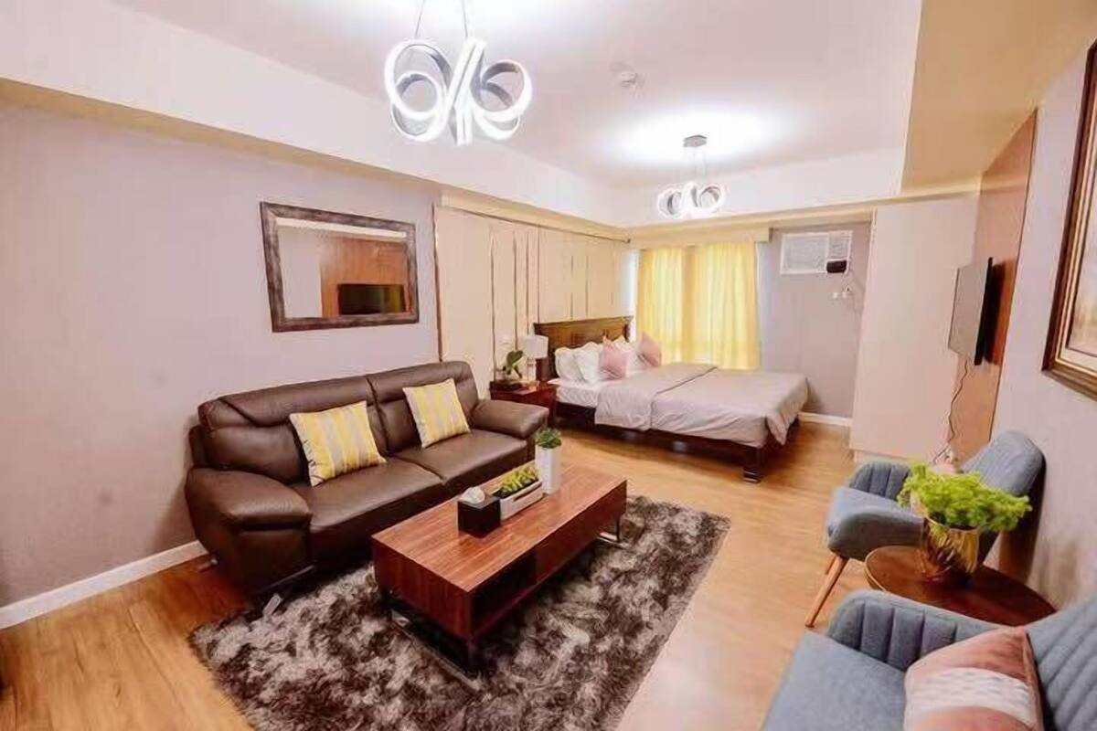 A modern living room with a brown leather sofa, a wooden coffee table, and a grey armchair.