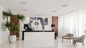 A modern reception area with a reception desk, two potted plants, and wicker chairs. - Davao Central Suites (Davao)