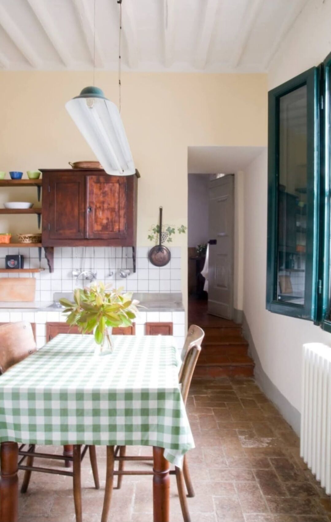 Un comedor con mantel a cuadros, sillas de madera y una lámpara colgante.