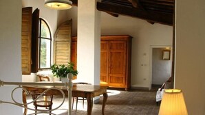 A room with a dining table, chairs, a lamp, and a large wooden cabinet. - Flower house, surrounded by greenery, overlooking a large garden. (Bacchereto)