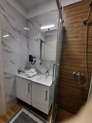 Regadera, secadora de cabello, toallas, papel de baño 