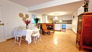 Un coin repas avec une table dressée pour quatre personnes, une chaise en bois et un vase rempli de fleurs.