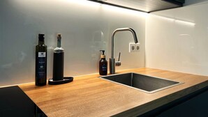 Una cocina moderna con un lavamanos de acero inoxidable, encimera de madera e iluminación debajo de los armarios.