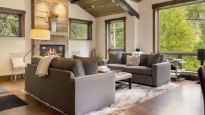 Una sala de estar moderna con chimenea, ventanas amplias y una pared decorativa de piedra.
